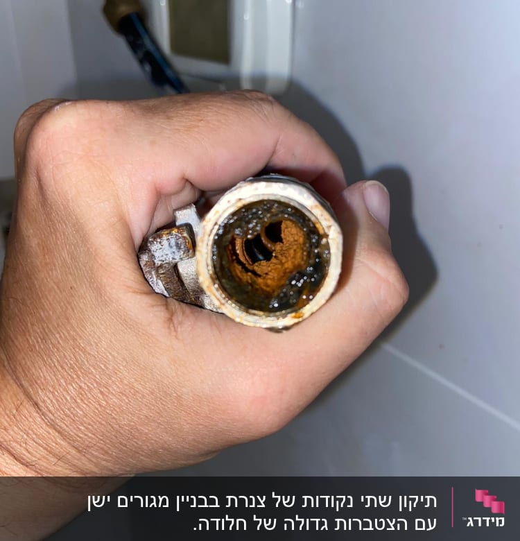 יד מחזיקה צינור חלוד עם לכלוך בפנים